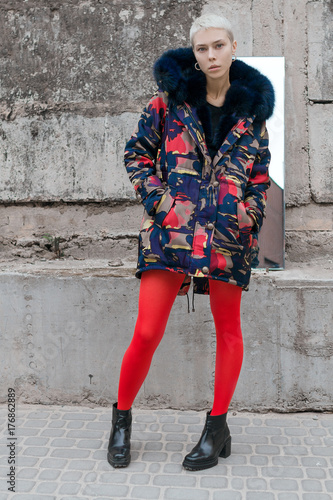 Stylish and beautiful girl with short hair on the street near the concrete wall