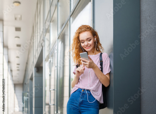 Young redhead woman listening to music outdoors © Prostock-studio