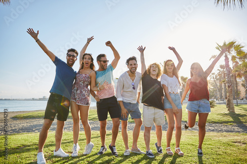 Group of friends raising hands together outside laughing