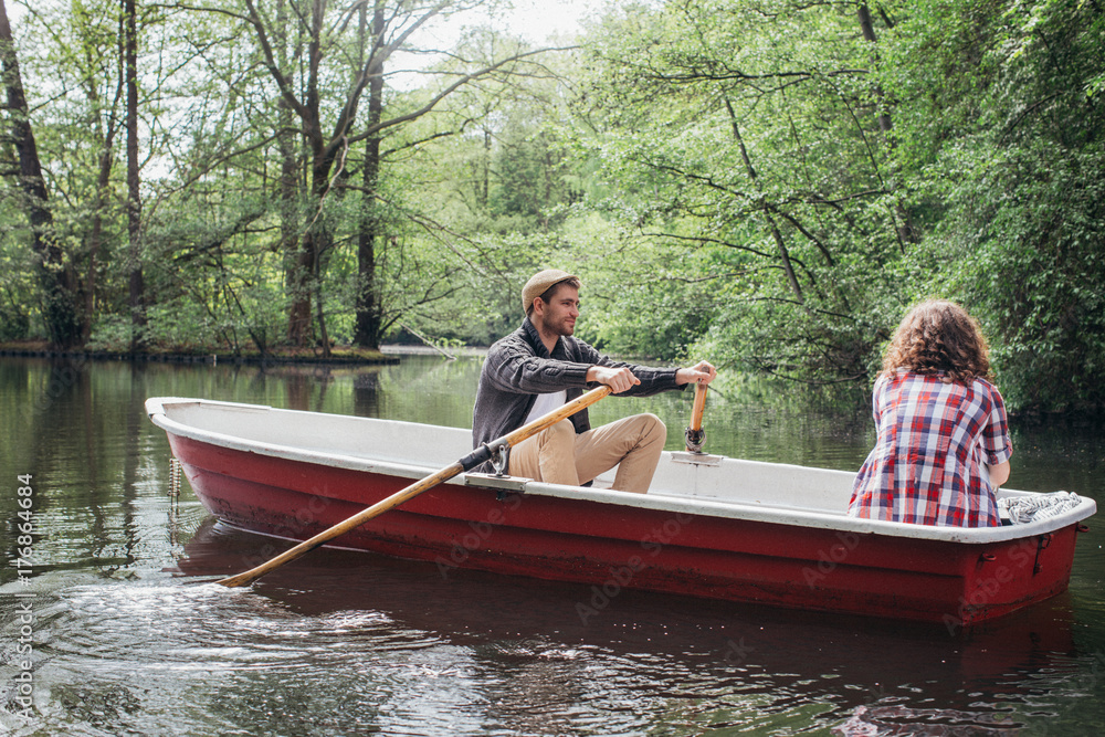 Young Caucasian Man and Woman on Rowboat on Forest Lake Young Caucasian Man and Woman on Rowboat on Forest Lake