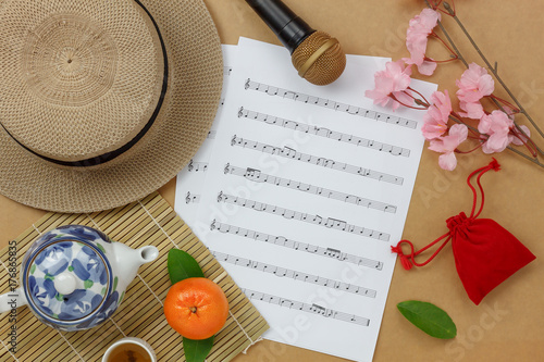 Overhead view of Chinese & Lunar new year and music sheet concept background.Paper notes with sign essential items for the Holidays.Variety objects on brown wooden at home office desk backdrop.
