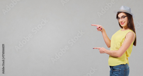 A girl points to a place for text on a gray background.