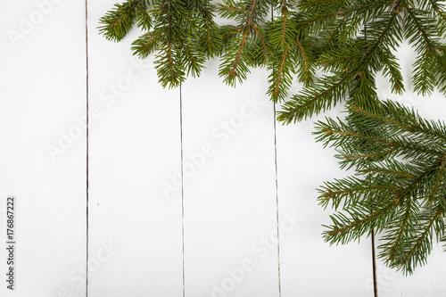 Fir branches on a white wooden background.