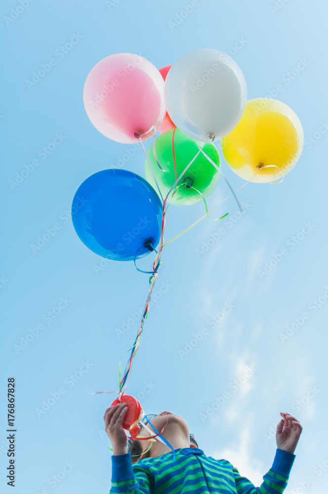 little boy stares up at the balloons above his head Stock Photo | Adobe ...