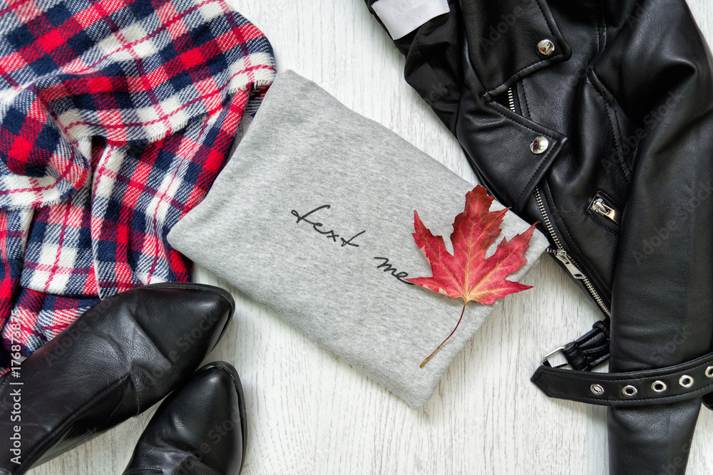 Gray sweater and maple leaf. Black jacket, checkered scarf and boots. Fashionable concept Gray sweater and maple leaf. Black jacket, checkered scarf and boots. Fashionable concept
