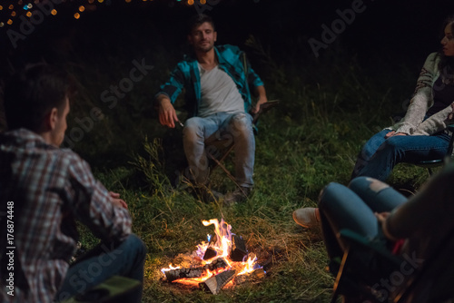 The young people sit near the bonfire. evening night time