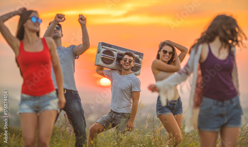 The happy friends dancing on the sunrise background
