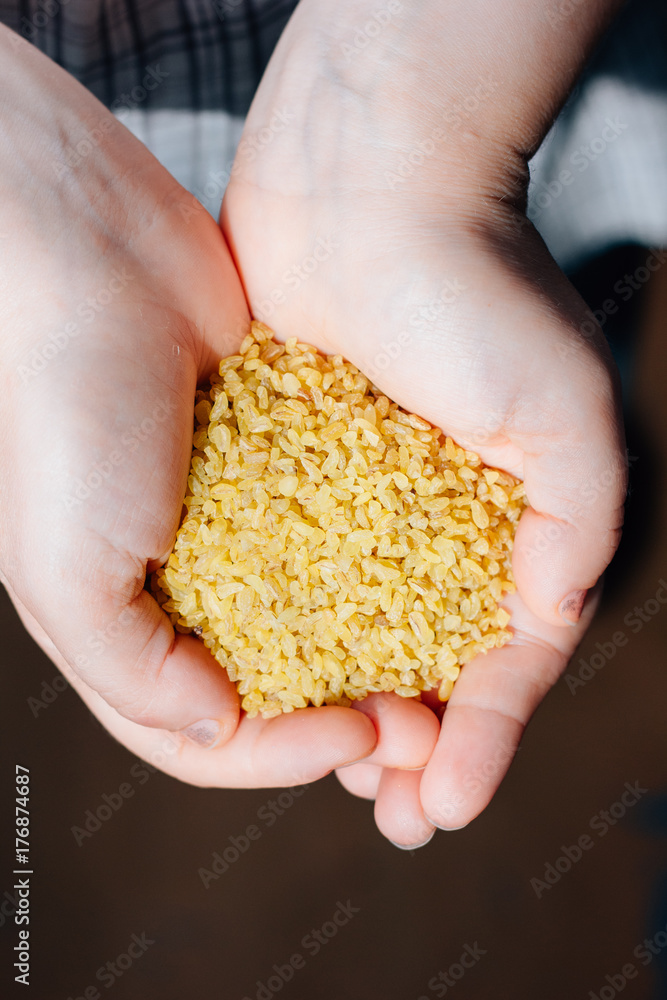 Woman holding natural organic bulgur cereal in hands. Woman holding natural organic bulgur cereal in hands.