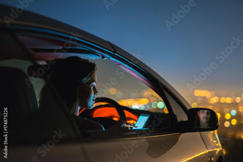 The woman phone in a car on the background of city lights. evening night time photo