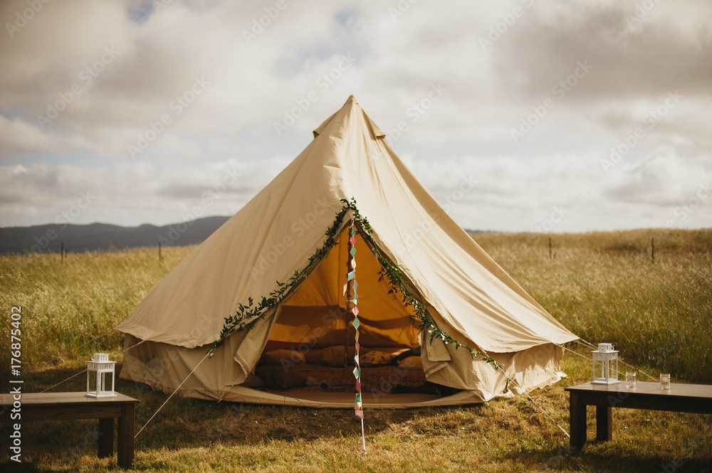 Fun floral and bunting covered canvas yurt tent in open field in California for wedding Fun floral and bunting covered canvas yurt tent in open field in California for wedding