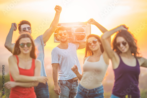 The happy people dancing with a boom box on the sunny background