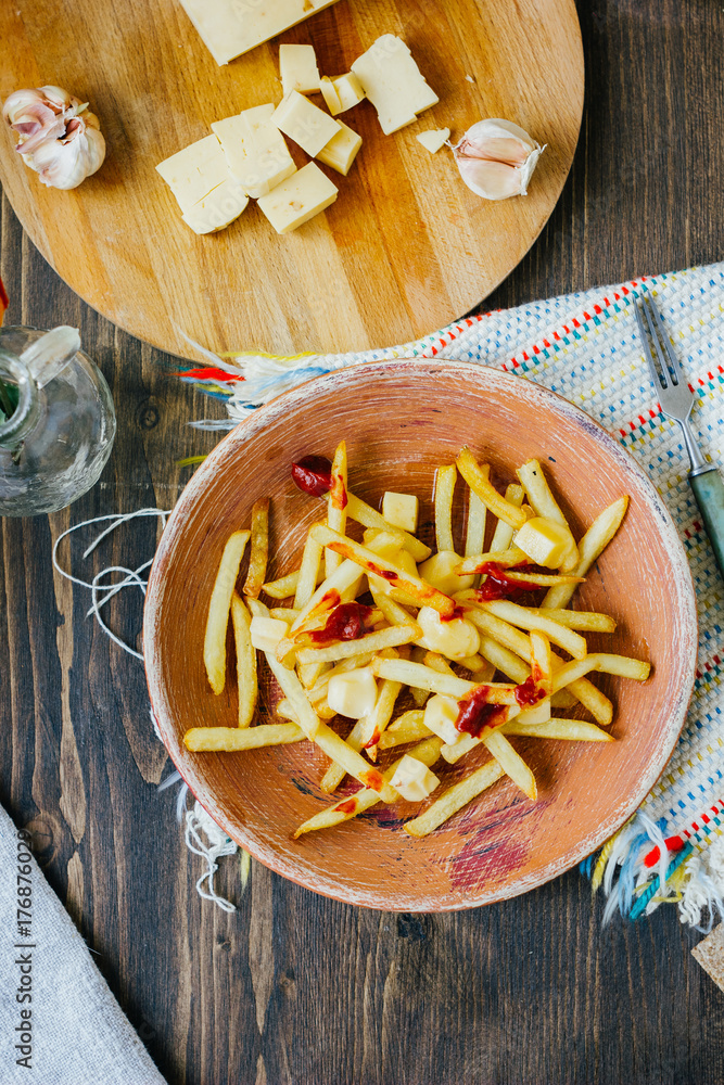 Poutine fries on black surface. Canadian dish with potatoes, cheese and sauce. Poutine fries on black surface. Canadian dish with potatoes, cheese and sauce.