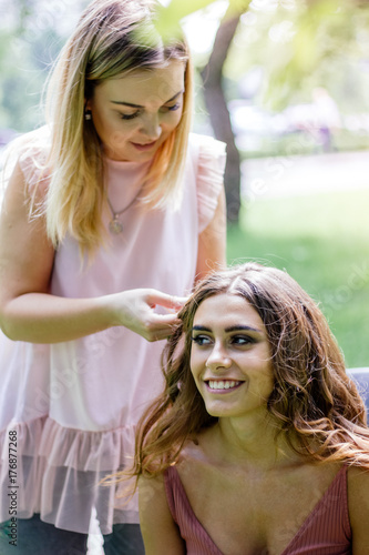 Braiding pigtales to young woman at outdoor session. photo