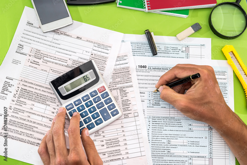 Obraz premium mężczyzna wypełniający formularz podatkowy długopisem, kalkulatorem