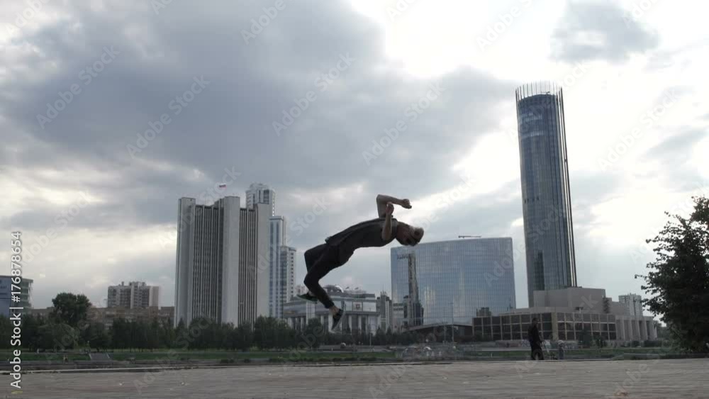 A cool guy does a somersault on the sidewalk. A cool guy does a somersault on the sidewalk.