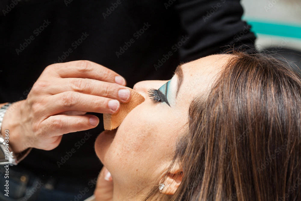 Makeup artist applying foundation using a sponge to a white woman Makeup artist applying foundation using a sponge to a white woman