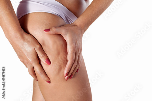Woman squeezing her thigh to show cellulite photo