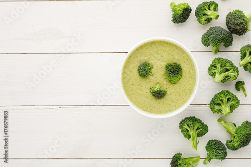cream soup in white bowl with broccoli on white wood background with free space for text.  top view 