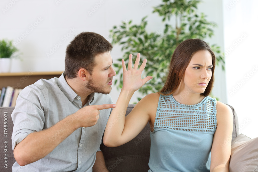 Angry couple fighting on a couch at home Angry couple fighting on a couch at home