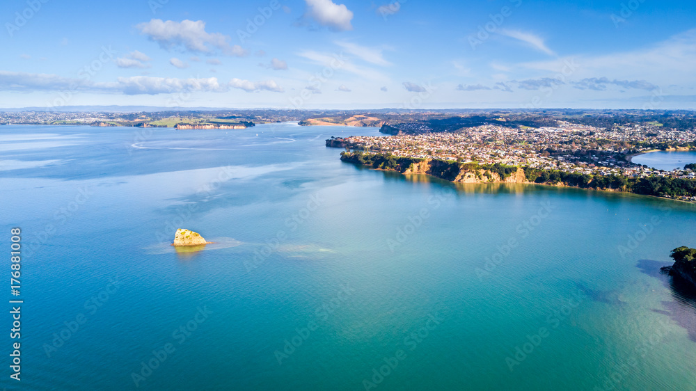 Aerial view on residential suburbs surrounded by sunny ocean harbour. Whangaparoa peninsula, Auckland, New Zealand.