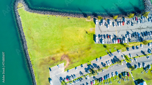 Aerial view on the entrance to the marina with boats resting along the pier and cars waiting on the parking space. Auckland, New Zealand photo