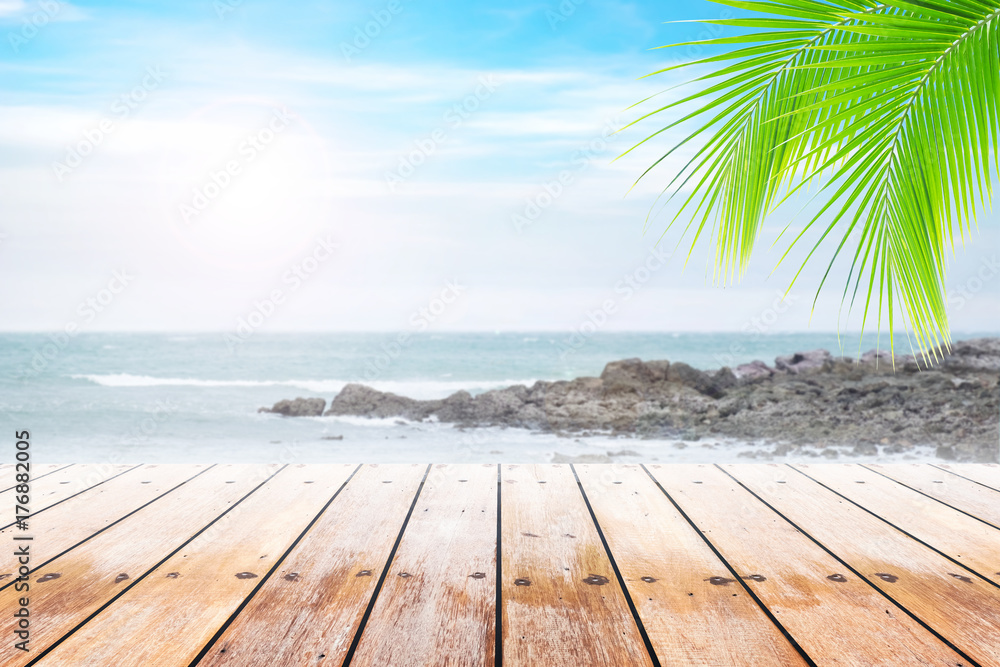 Fototapeta premium Empty wooden table and coconut leaves with party on beach blurred background in summer time.