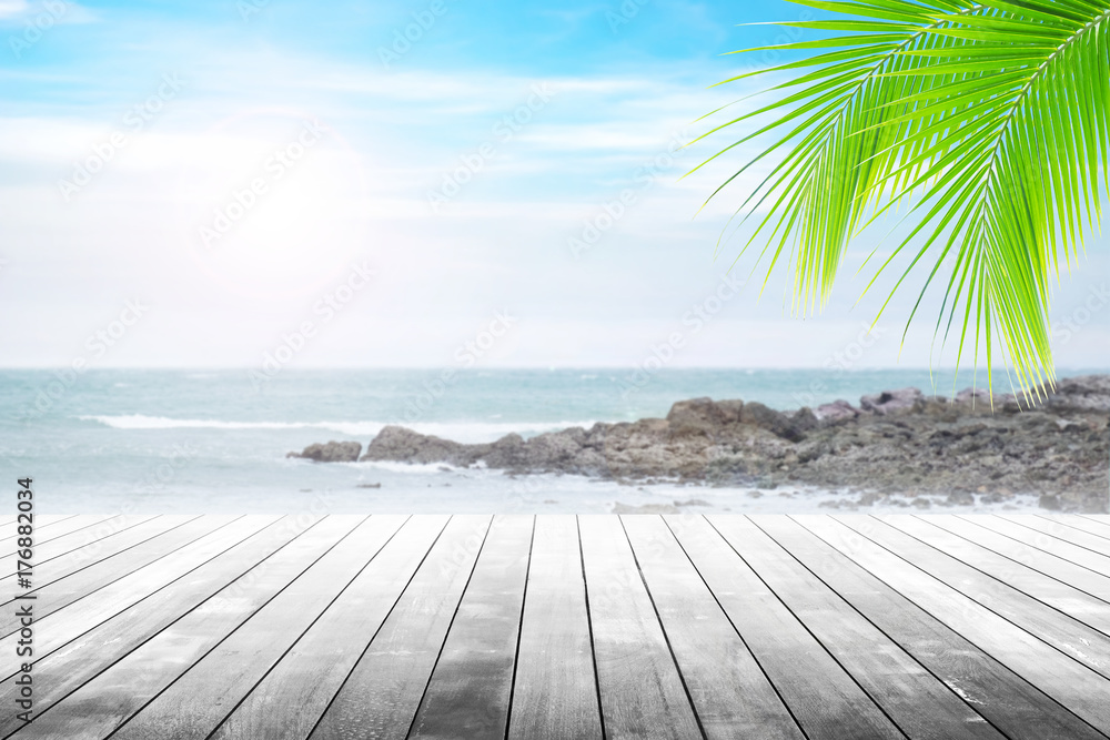 Empty wooden table and coconut leaves with party on beach blurred background in summer time.