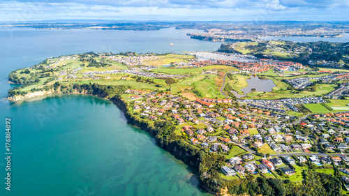 Aerial view on residential suburbs surrounded by sunny ocean harbour. Whangaparoa peninsula, Auckland, New Zealand