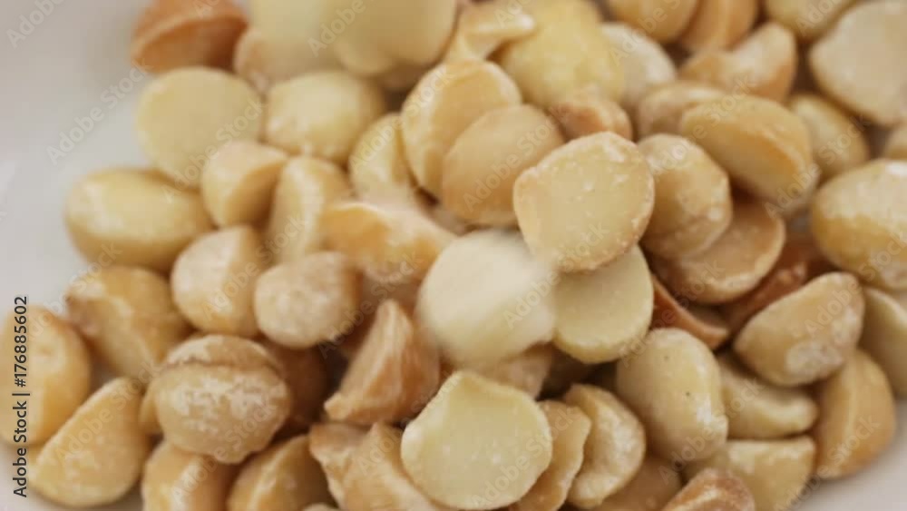 Video of macadamia nuts slowly spilling into a bowl. Video of macadamia nuts slowly spilling into a bowl.