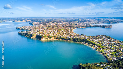 Fototapeta Naklejka Na Ścianę i Meble -  Aerial view on residential suburbs surrounded by sunny ocean harbour. Whangaparoa peninsula, Auckland, New Zealand