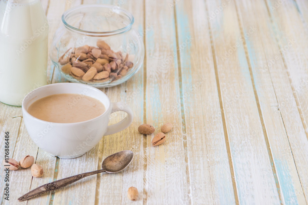 Coffee with milk and pistachios on wooden table, copy space Coffee with milk and pistachios on wooden table, copy space