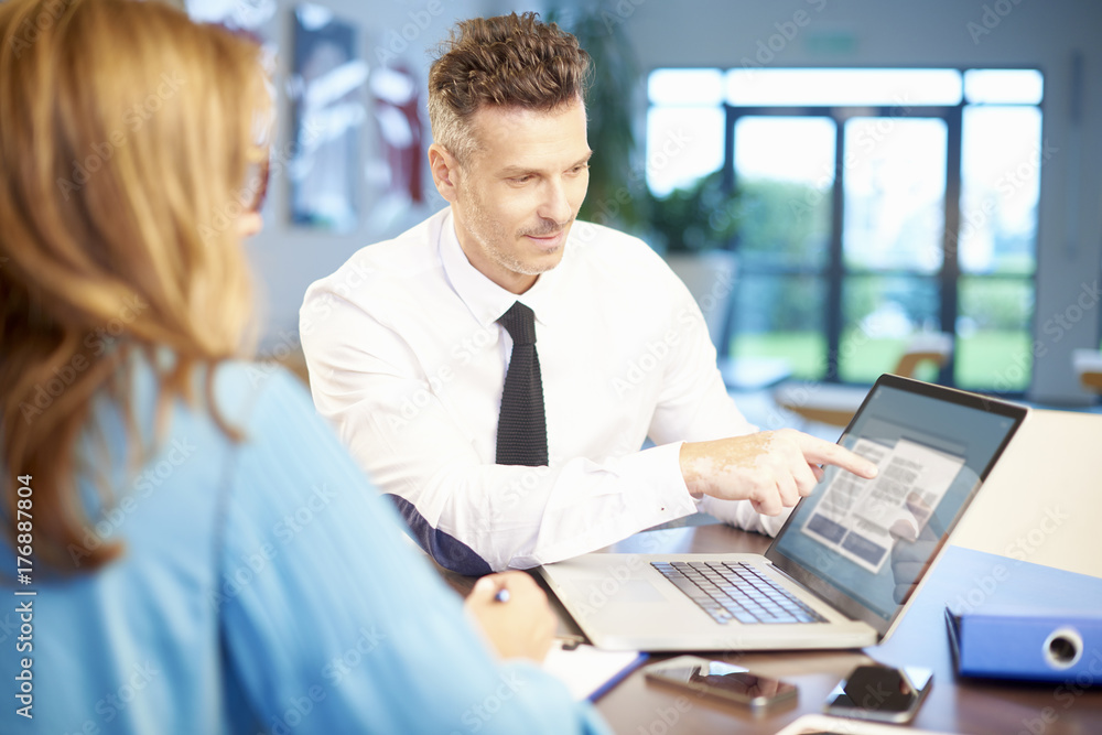 Teamwork at the office. Shot of a businessman sitting at desk in front of laptop and consulting with professional financial businesswoman. Teamwork at the office. Shot of a businessman sitting at desk in front of laptop and consulting with professional financial businesswoman.