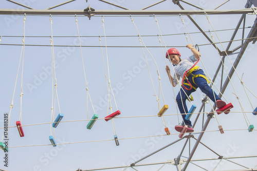 Little girl climbing on an outdoor ropes course.