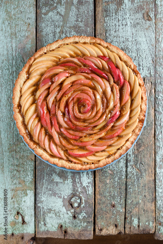 Homemade gourmet open pie with apple rose and frangipane filling on rustic textured blue wooden background above view