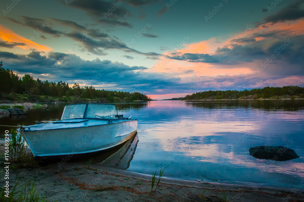 Boat on the shore. Dawn. Reflection of the sunrise in the water. Karelia. Russia. Ladoga lake.