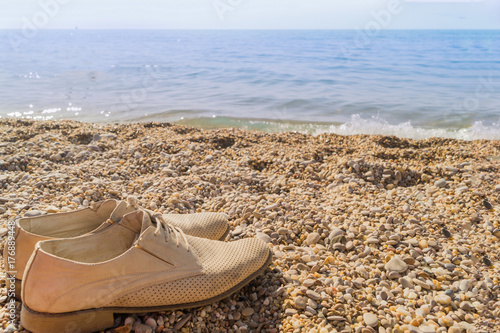 Beige man's shoes on the beach on a sunny day