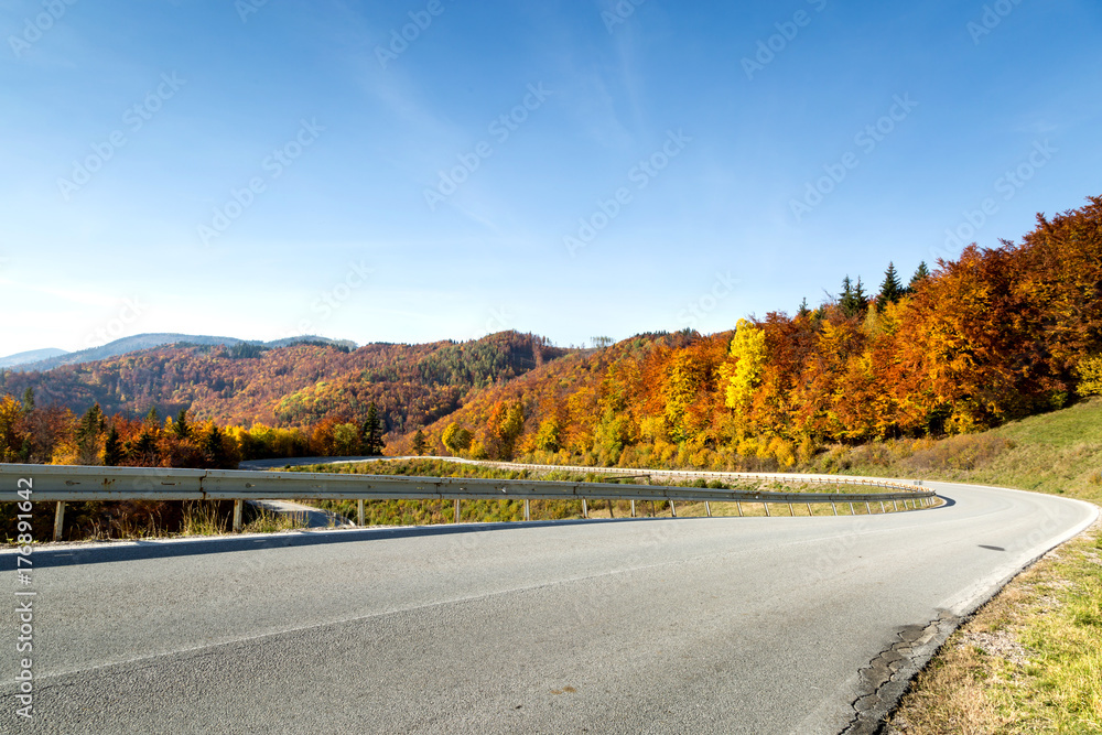 Asphalt road in the mountains between colorful autumn trees. Asphalt road in the mountains between colorful autumn trees.