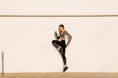 Full length photo of young sport woman jumping near white wall