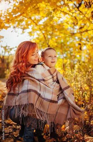 Happy mother and her little son walking and having fun in autumn forest.