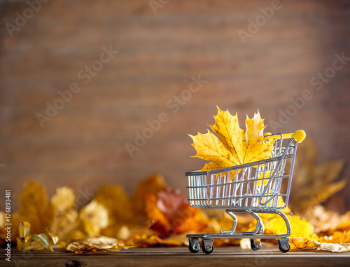 Vintage cart with maple tree leaves on yellow wooden background