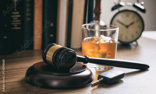 Law gavel, alcohol and car keys on a wooden desk, dark background photo