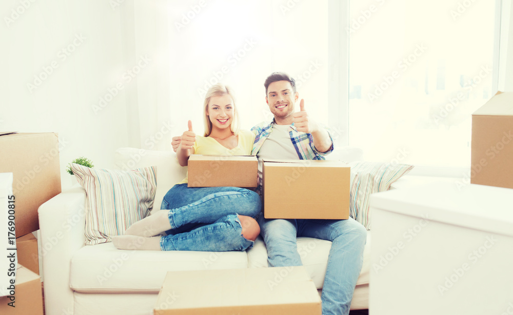 happy couple with boxes showing thumbs up at home happy couple with boxes showing thumbs up at home