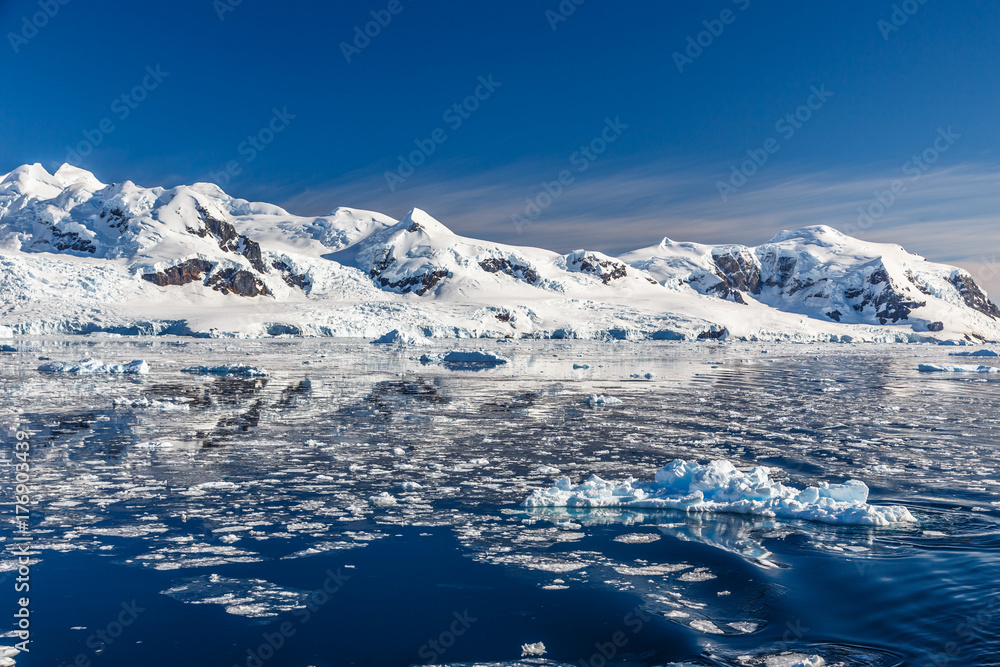 Sunset over idyllic lagoon with mountains and icebergs in the background at the Lemaire Strait, Antarctica