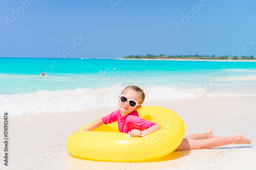 Happy little girl with inflatable rubber circle having fun on the beach