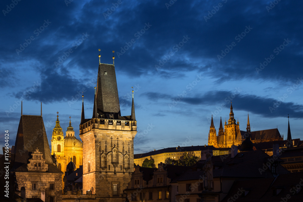 Fototapeta premium View of lit Lesser Town Bridge Towers, St. Nicholas Church and Prague (Hradcany) Castle at the Mala Strana (Lesser Town) in Prague, Czech Republic, in the evening. Copy space.