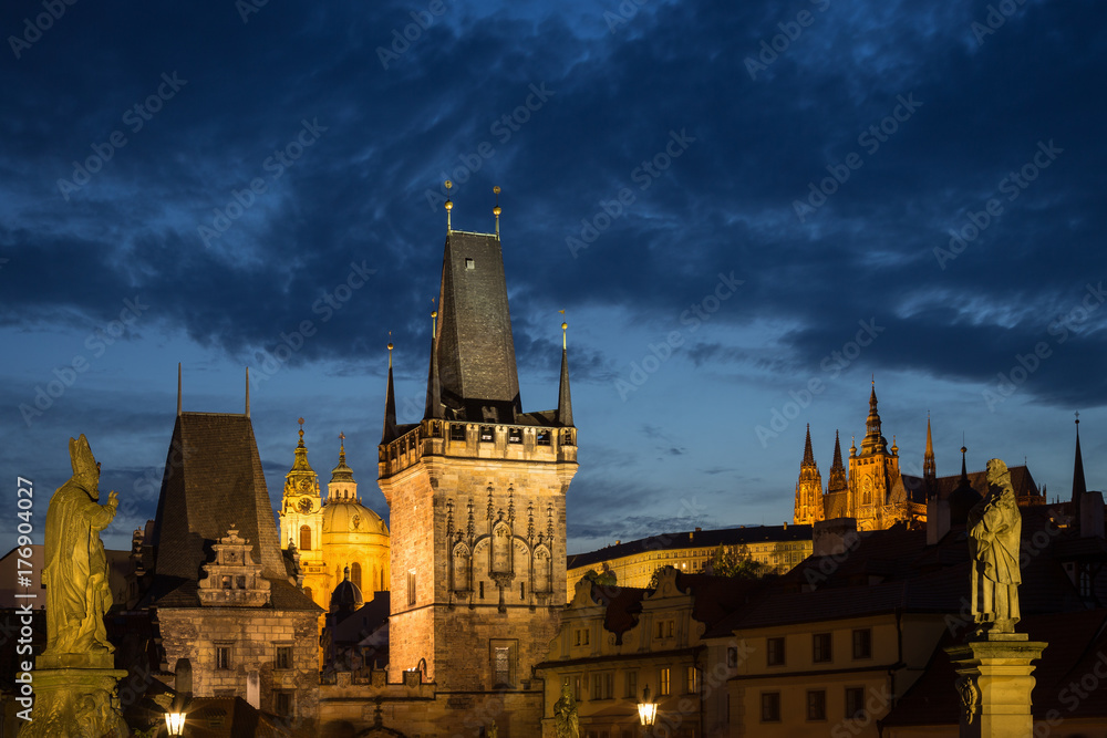 View of lit statues, Lesser Town Bridge Towers, St. Nicholas Church and Prague (Hradcany) Castle at the Mala Strana (Lesser Town) in Prague, Czech Republic, in the evening. Copy space.