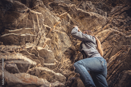 Courage woman achieving her goal climbing up on rock 