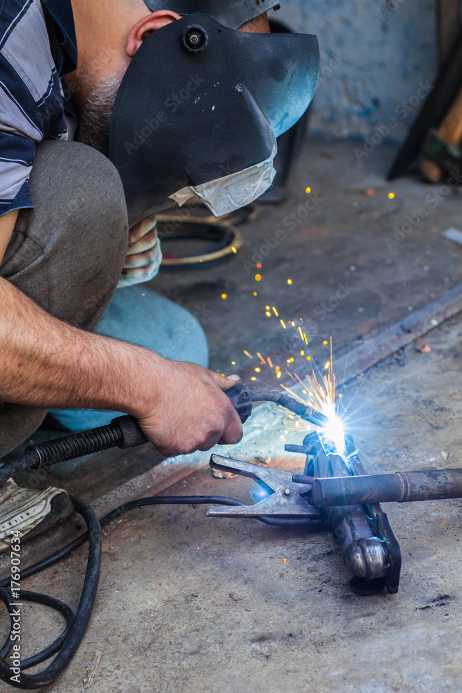 Car mechanic welding car part with torch. Car mechanic welding car part with torch.