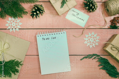 Preparation of Christmas gifts. Gift boxes are packed with kraft paper decored branches fir. to-do list for winter holidays. Xmas background. Still decor. Natural ornament. Top view
