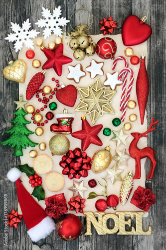 Symbols of christmas background with bauble decorations, noel sign, mince pies, gingerbread cookies and foil wrapped chocolates on parchment paper and rustic wood.